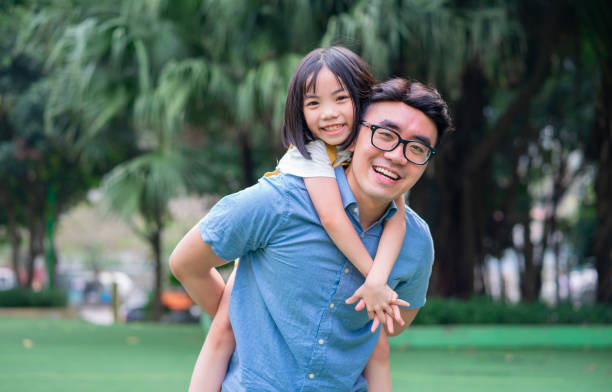 Image of Asian father and daughter playing together at park